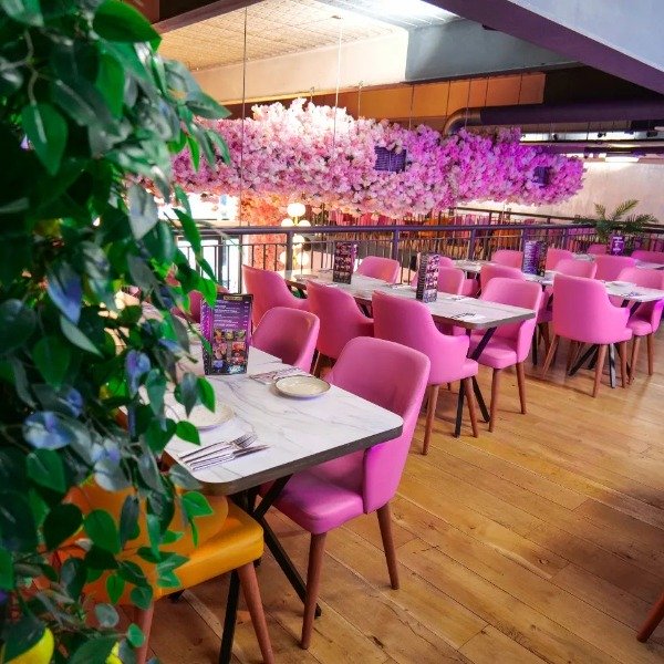 tables at Sultans, with green plant in the foreground and pink flowers hanging from the ceiling