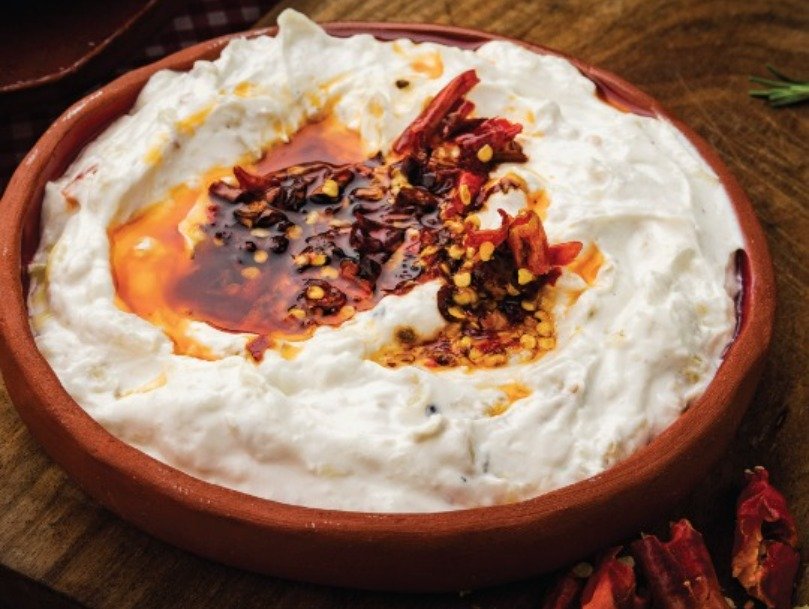 Terracotta dish filled with a dip, topped with chillies and oil.