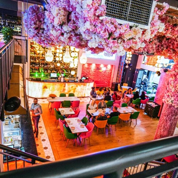 birds eye view of the restaurant, people dining and hundreds of pink flowers hanging from the ceiling